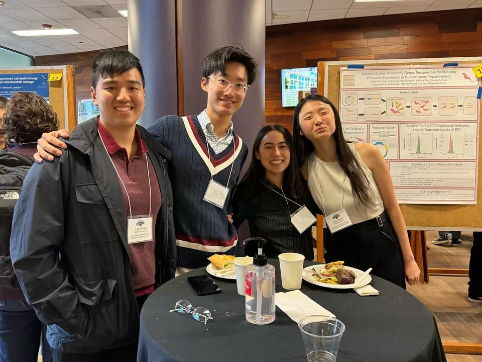 4 students taking a picture together around a round table at a conference 