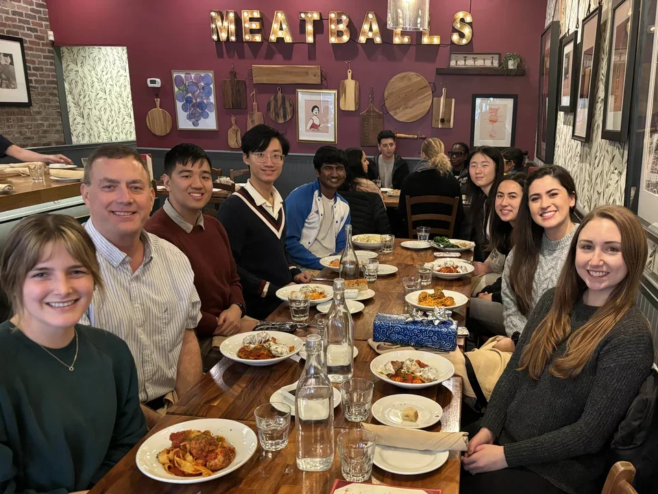 group of students and their PI eating pasta around a table at a restaurant