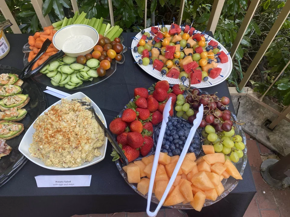A table with several trays of food, including fruits and vegetables.