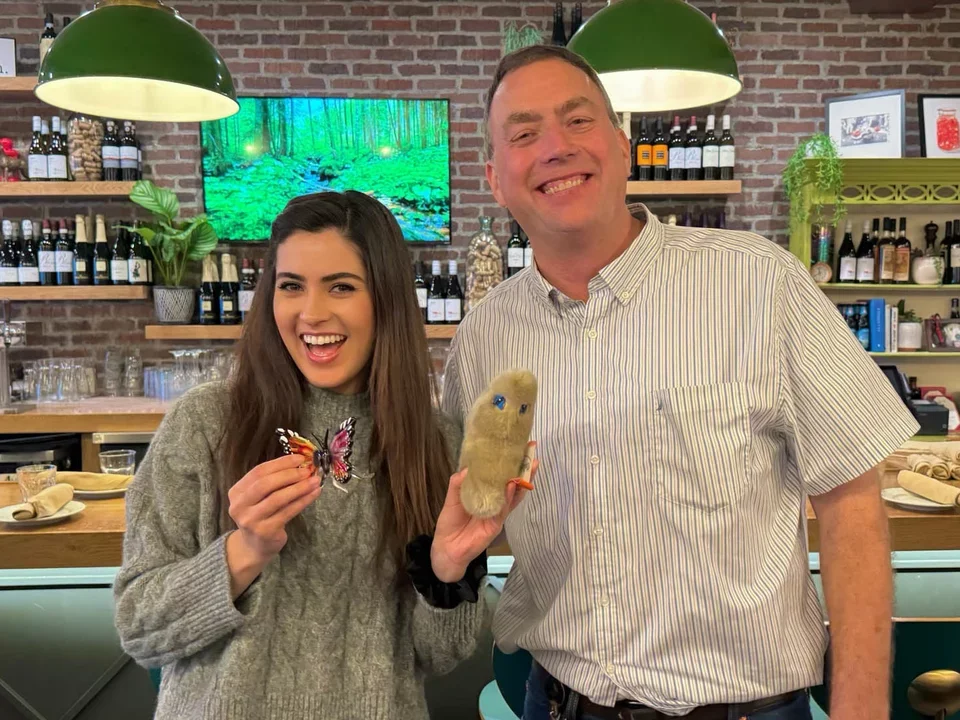 Student holding a glass butterfly standing next to her PI