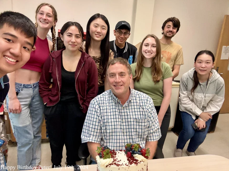 group of students with their PI in front of birthday cake