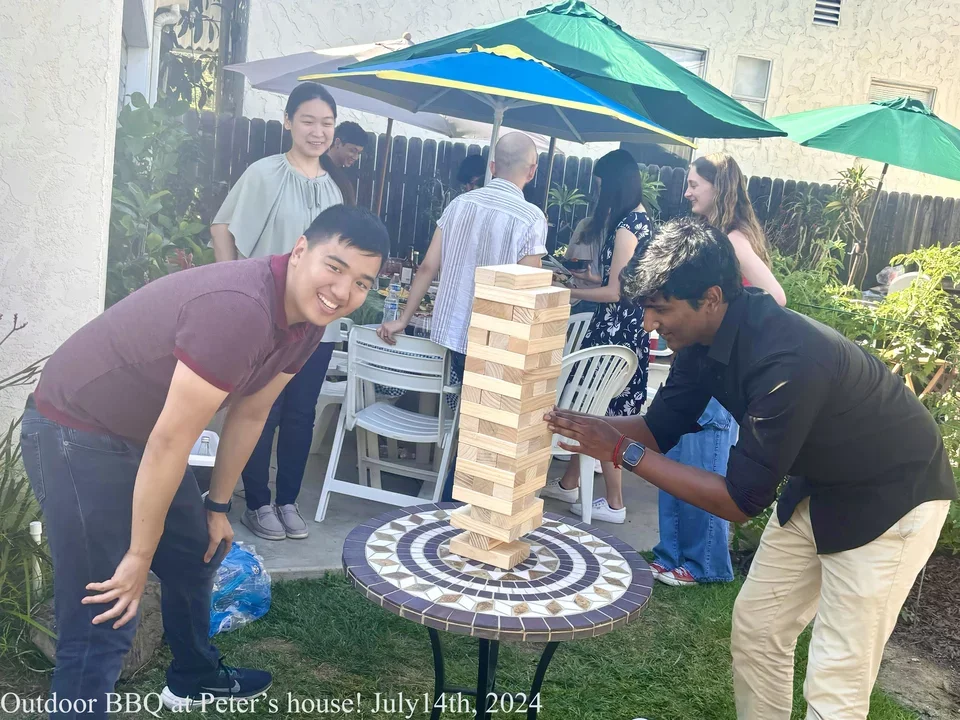two students playing jenga in backyard