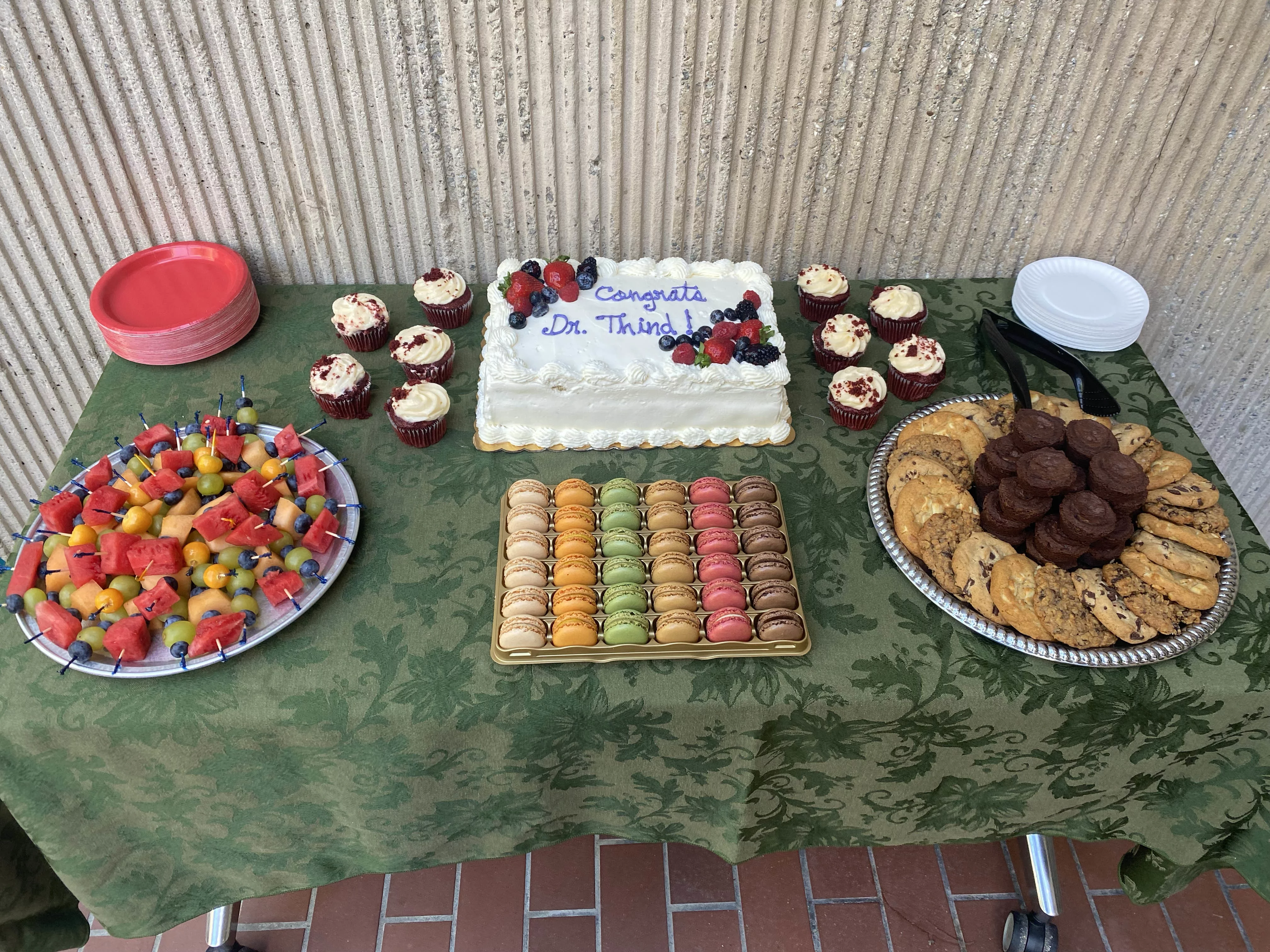 A dessert table with a large cake and other treats. The cake says congrats Dr. Thind on it.