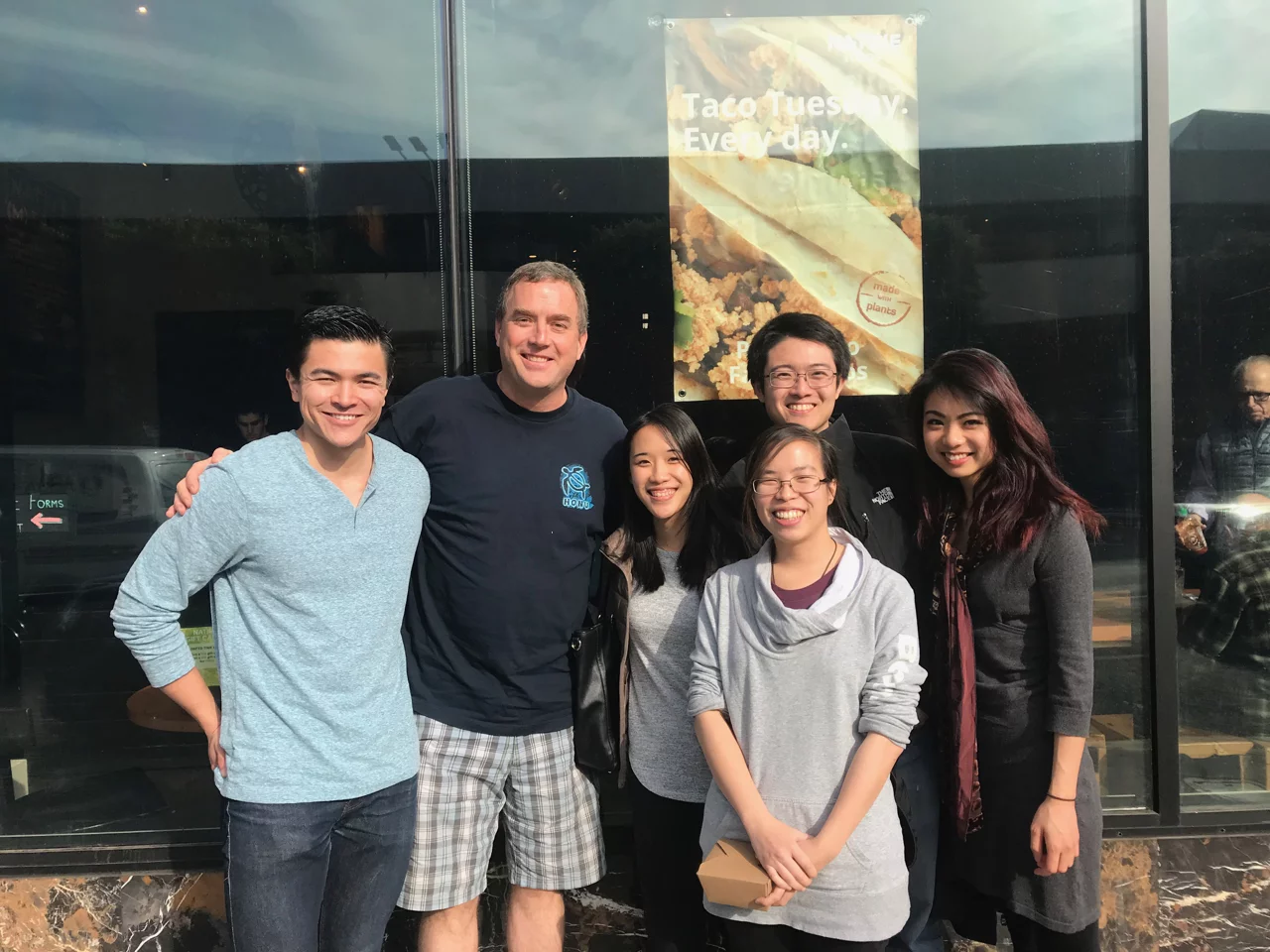 Members of the lab are posing for a photo during a lunch social at a restaurant.