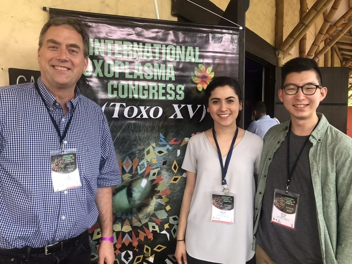 Two students at the International Toxoplasma Congress take a photo with their PI.